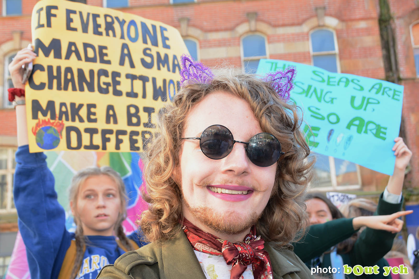 Young man in dark glasses in front of placards at the strike for climate protest in Belfast. Photo 8929 by Bout Yeh photographers Belfast