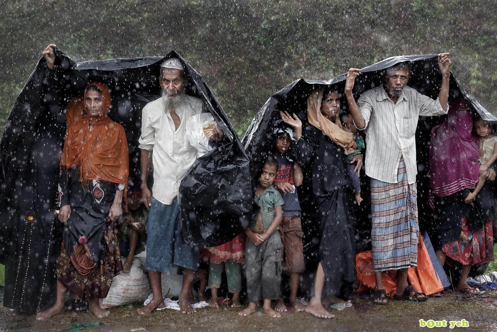 Rohingya refugees shelter from the rain in a camp in Cox's Bazar, Bangladesh - photo by Cathal McNaughton shared by Bout Yeh photographers Belfast