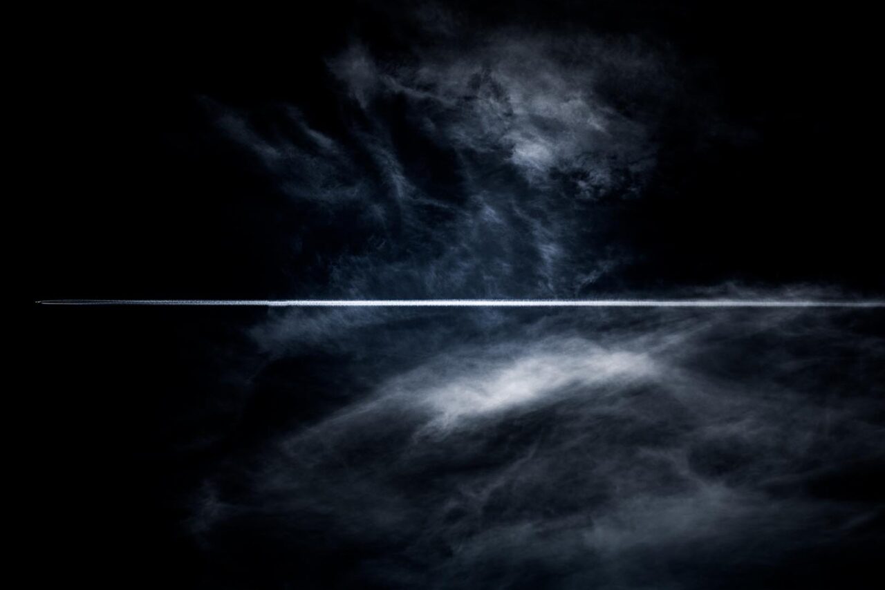 A plane and it's jet stream cut through clouds over Newtownabbey, Northern Ireland - Fine art photograph of Ireland by Stephen S T Bradley entitled Miniscule
